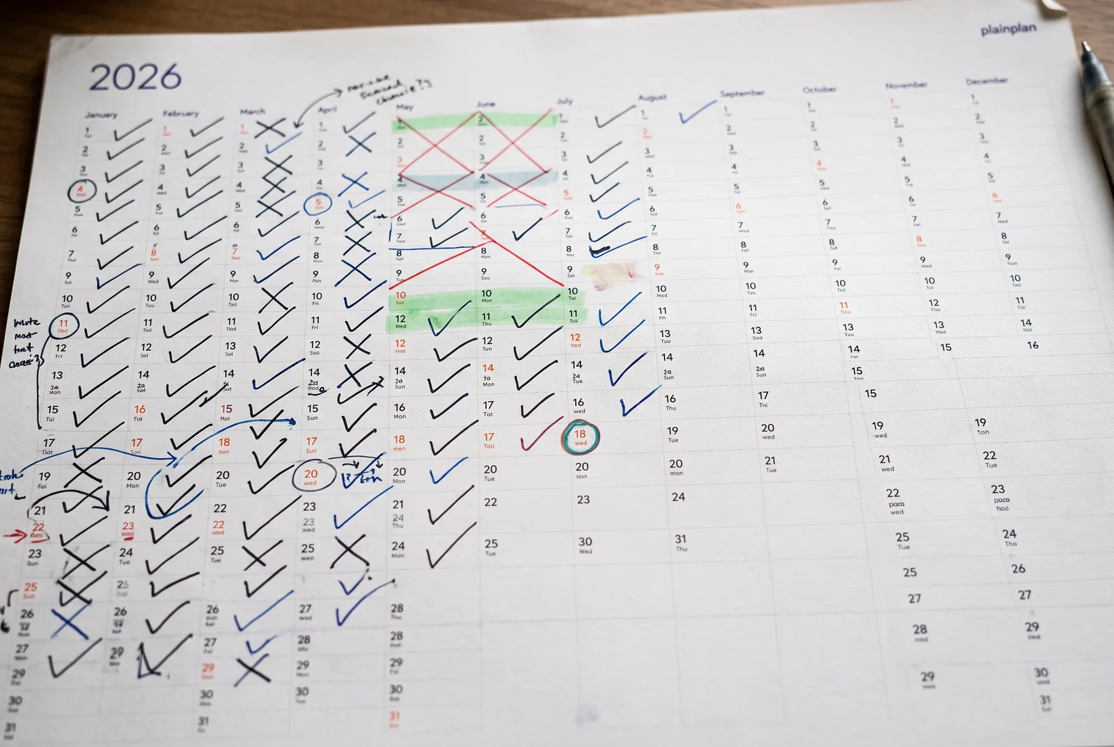 plainplan 2027 Vertical planner on a hallway wall next to a shoe rack with running shoes; a marathon date circled, long runs highlighted in one colour rising week by week, weeks numbered as a countdown in the margin