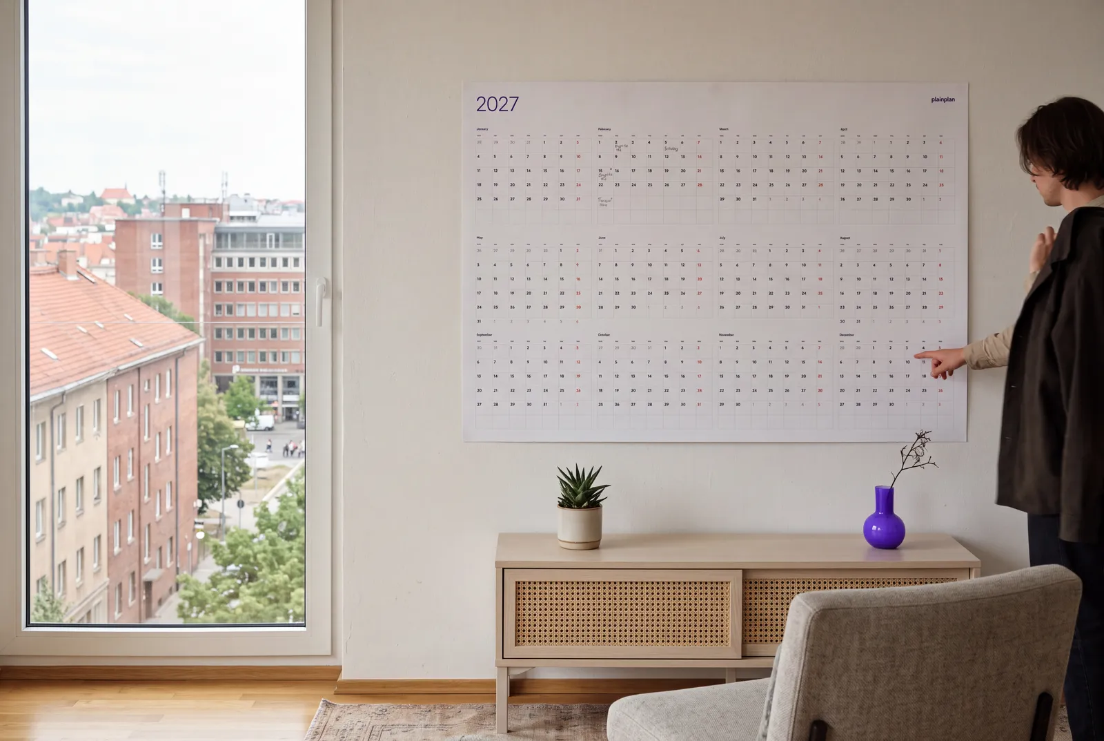 Man checking a plainplan 2027 wall planner in a city apartment