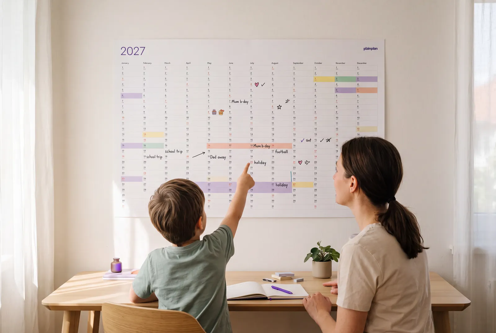 Family adding school events to a yearly wall planner in the kitchen