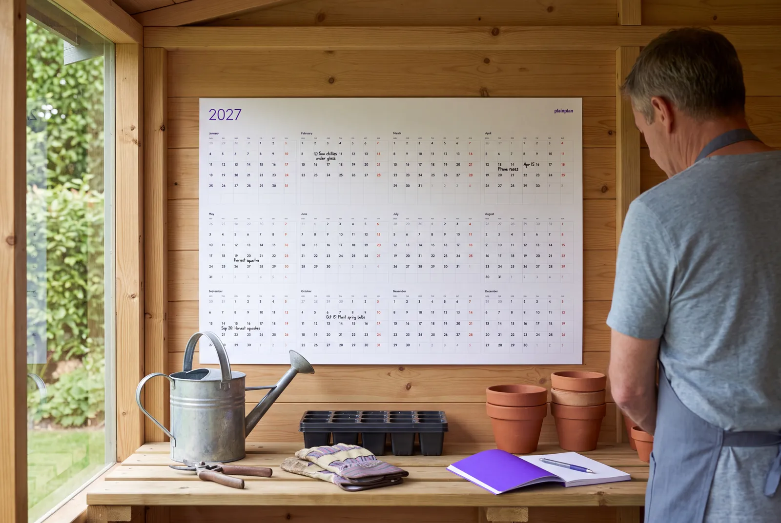 Seasonal garden jobs marked on a plainplan 2027 wall planner in a garden shed