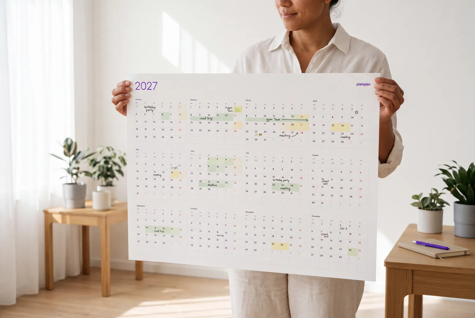 A large printed wall planner held up against a wall to check the size